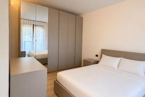 A hotel room with a bed, bedside tables, a wardrobe, and a window with curtains. - Venice Easy Stay | New Apartment with Parking (Mestre)