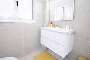 Un baño con un tocador blanco, un espejo y un inodoro.