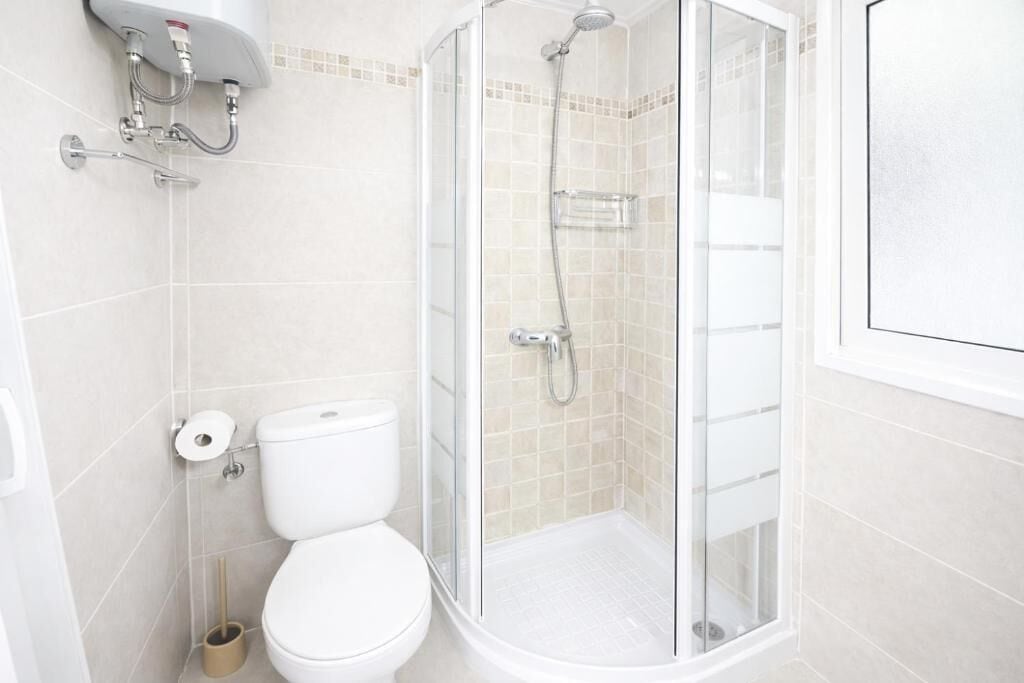 Un baño con inodoro, ducha con puerta de cristal y barra para toallas.