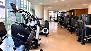 A gym with cardio machines, weight training equipment, and a large window providing natural light. - Luxury 3BR Loft with Private Pool & City Views in Makati (Makati City)