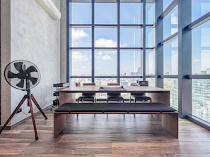 Een moderne kantoorruimte met een groot raam, een bureau, stoelen en een ventilator.