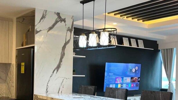 A modern kitchen with a marble countertop, a built-in refrigerator, and a flat-screen TV. - Luxury 3BR Loft with Private Pool & City Views in Makati (Makati City)