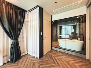 Een moderne badkamer met een grote spiegel, een wit wastafelmeubel en een houten vloer.