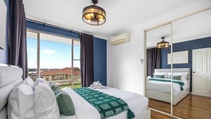 Una camera d'hotel con un letto grande, uno specchio, vista dalla finestra e una ventola a soffitto.