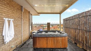 A hot tub on a patio with a brick wall and a bamboo fence. - The Beach House|4BR+Spa+Jacuzzi|2 Min Coogee Beach (Coogee)