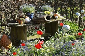 Un jardin agrémenté d’une structure en bois où sont disposées différentes plantes et fleurs en pot.