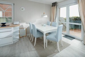 A modern kitchen with a dining area, a clock on the wall, and a view of the outside. - Holiday apartment in Juist with swimming pool (Juist)