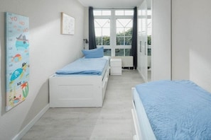 A bedroom with two beds, a window, and a calendar on the wall. - Holiday apartment in Juist with swimming pool (Juist)