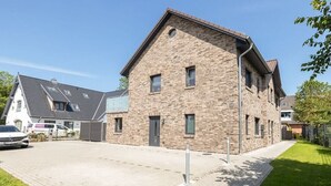 Een woongebouw met een bakstenen gevel, meerdere ramen en een verharde oprit.