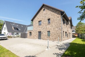 Un edificio residenziale con facciata in mattoni, diverse finestre e vialetto lastricato.