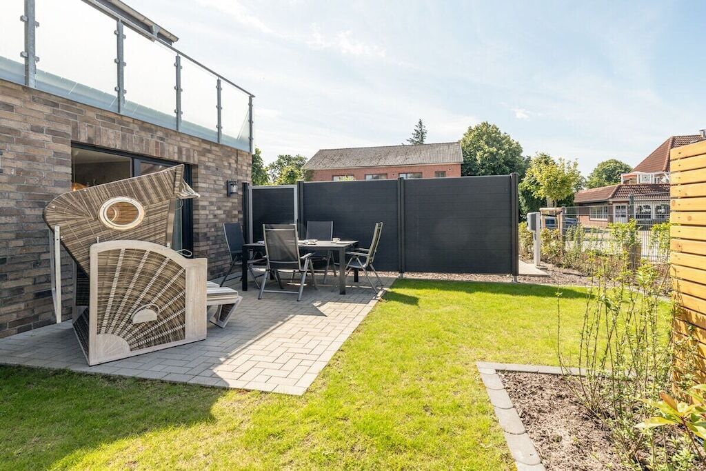 Une terrasse avec une table et des chaises, une structure décorative en bois et un mur en briques.