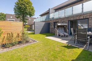 Un cortile residenziale con patio, una recinzione in legno e una zona relax con sedie e tavolo.