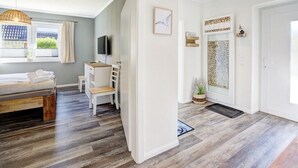 Een slaapkamer met een bed, een bureau, een stoel, een televisie en een raam met gordijnen.