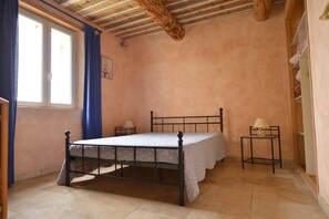 A bedroom with a bed, a bedside table, a lamp, and a window with curtains. - Just a short walk from the Luberon Mountains—accommodations for up to six people (Maubec)