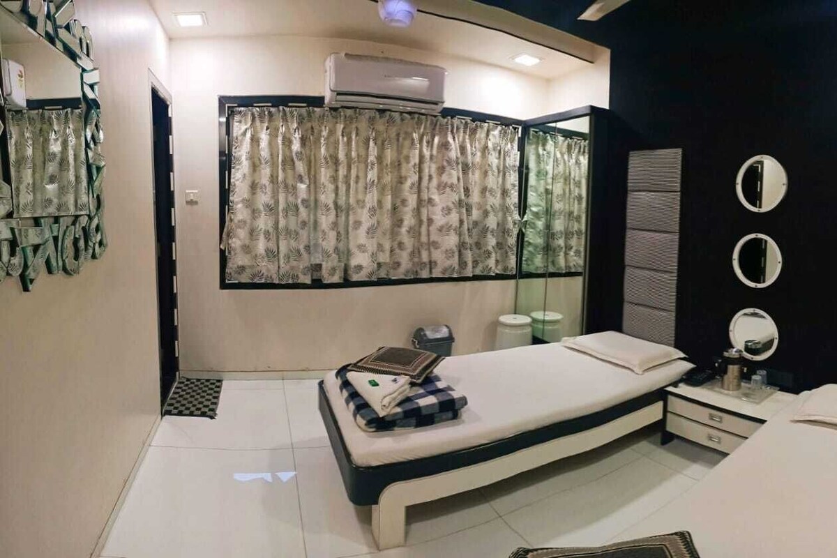 A bedroom with a bed, bedside tables, a mirror, and a window with curtains.