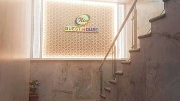A staircase leading to a room with a sign reading 'Nice Guest House.'