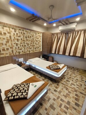 A modern room with two beds, a ceiling fan, and an air conditioning unit. - Nice Guest House (Mumbai)