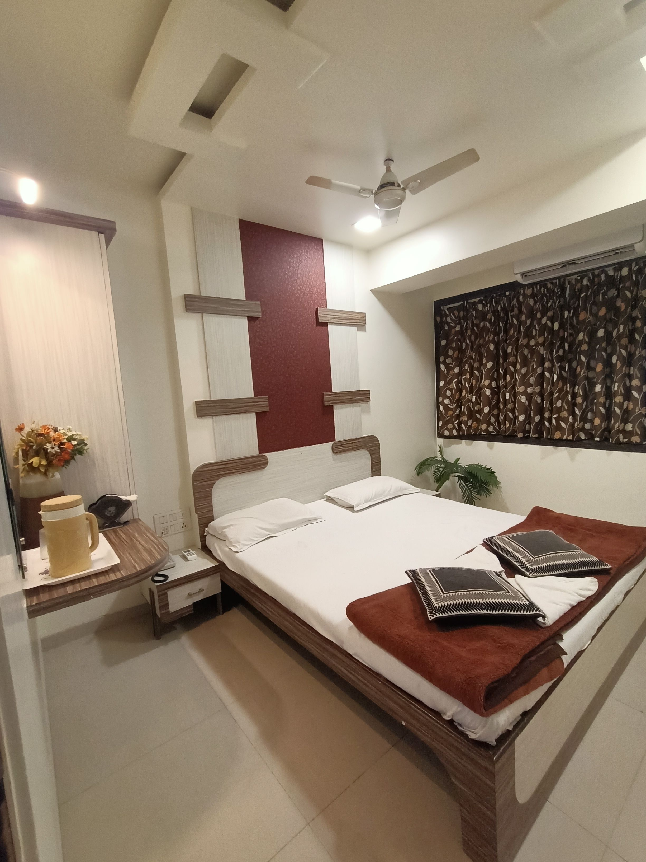 A bedroom with a bed, bedside table, nightstand, and a ceiling fan.