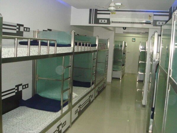 A corridor with bunk beds, a ceiling fan, and an air conditioning unit. - Nice Guest House (Mumbai)