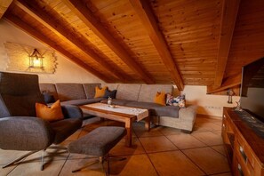 Ein gemütliches Wohnzimmer im Loft-Stil mit hoher Decke, einem Ecksofa, einem Couchtisch und einem Fernseher.