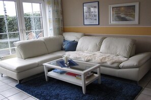 A living room with a white sofa, a glass coffee table, and a blue rug. - Holiday home in Dangast with swimming pool (Dangast)
