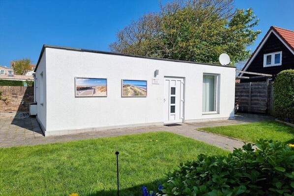 A small, single-story building with a white exterior, a door, and two windows. - DO01 Holiday bungalow near the beach and city (DOMBURG)