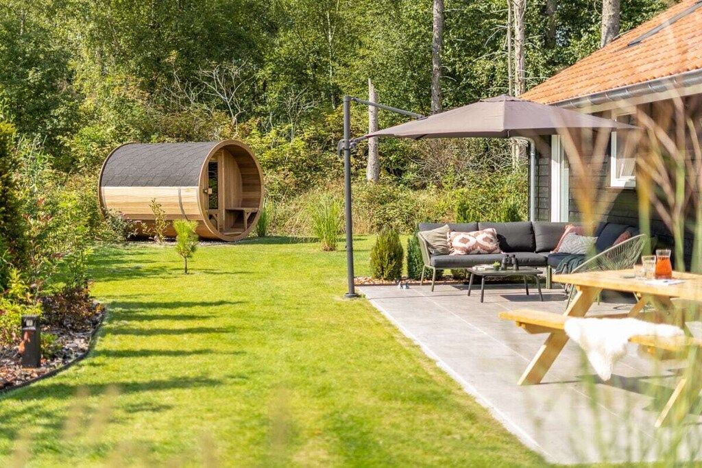 Een houten vatgebouw met een terras, zitplaatsen buiten en een kleine boom.