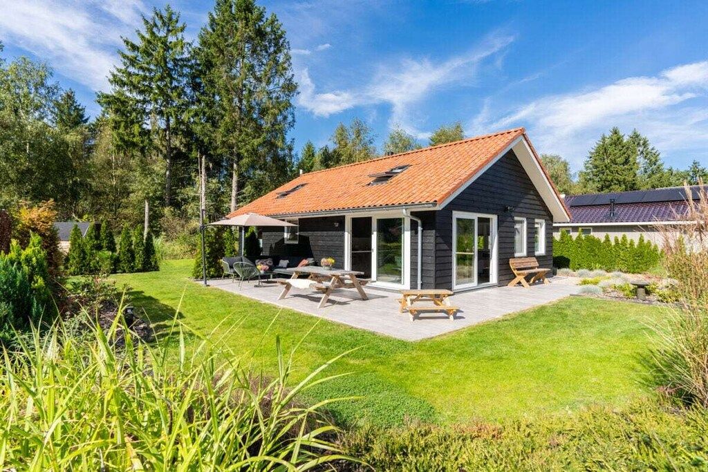 Une maison moderne dotée d’un patio couvert, d’un espace salon extérieur et d’une pelouse bien entretenue.