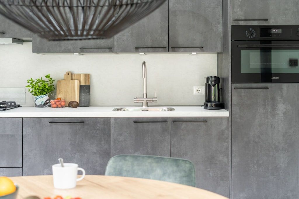 A modern kitchen with a stainless steel sink, a coffee maker, and a built-in oven.