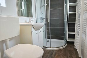 A modern bathroom with a toilet, sink, and glass shower enclosure. - Holiday home with 1 bedroom (Oostkapelle)