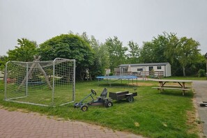 A grassy area with a soccer goal, a small trailer, and a picnic table. - Holiday home with 1 bedroom (Oostkapelle)