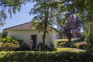 Una casa con techo de tejas, rodeada de vegetación exuberante y un jardín cuidado.