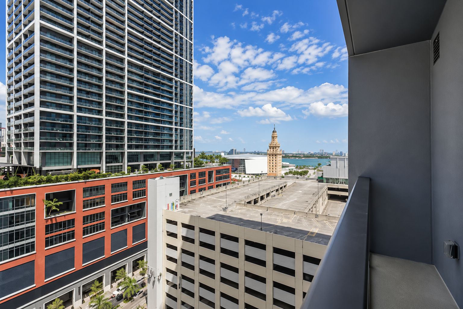 A high-rise building with a clear view of a distant tower and a body of water.