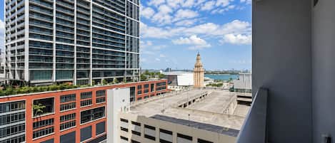 A high-rise building with a clear view of a distant tower and a body of water.