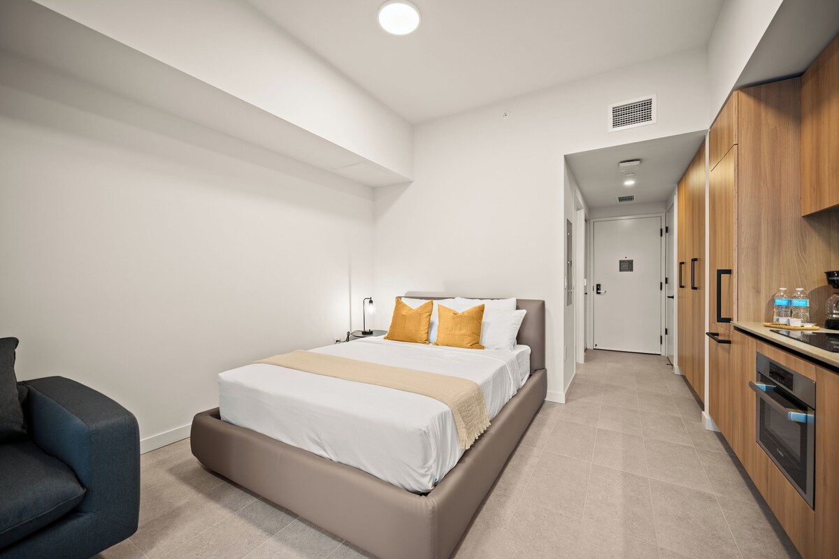 Una habitación de hotel moderna con cama, escritorio y kitchenette.