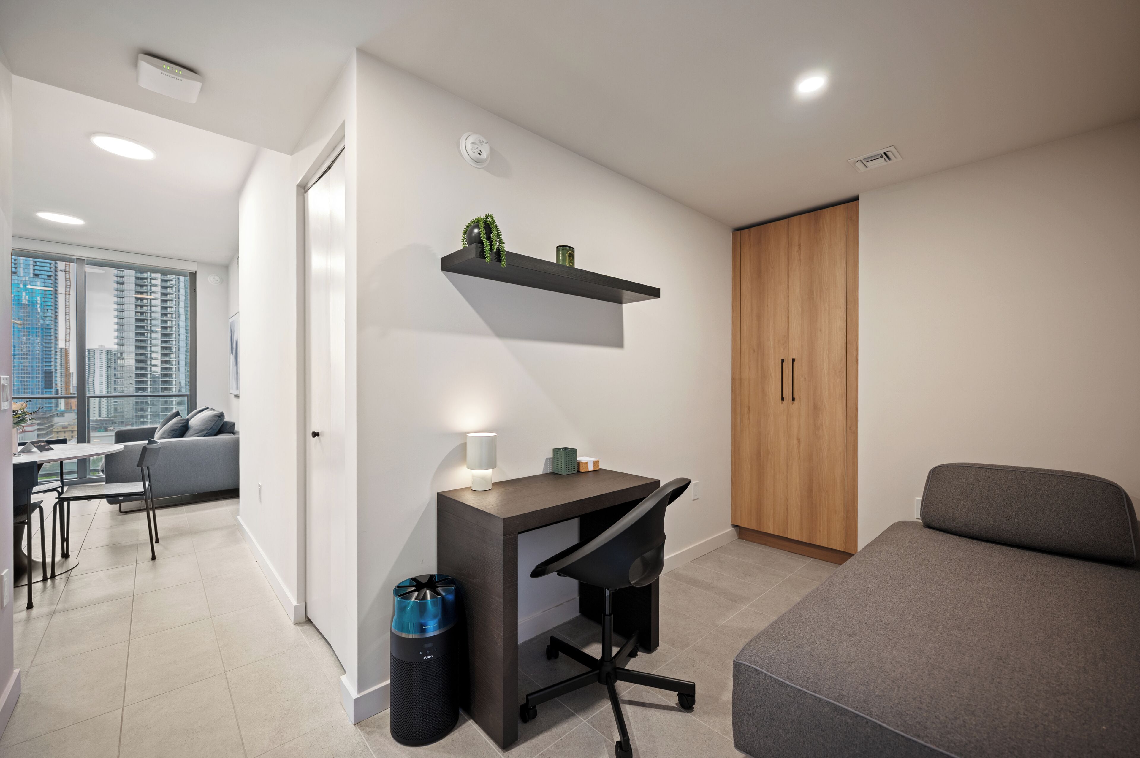 A modern, well-lit room with a desk, chair, and a grey sofa.