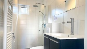 Uma casa de banho moderna com sanita, chuveiro e lavatório.