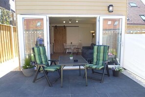 Une terrasse ouverte avec une table et des chaises, un canapé et des plantes en pot.
