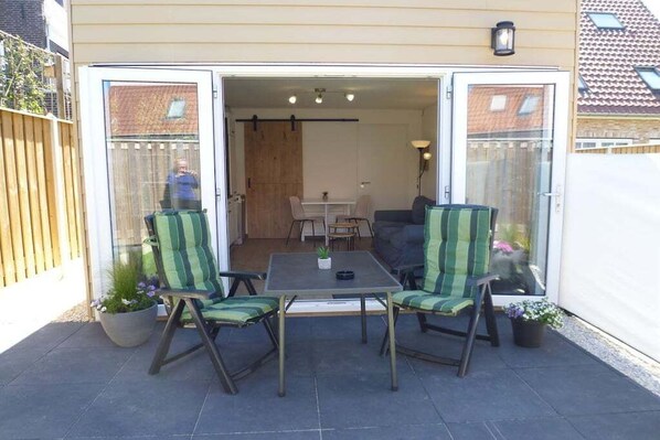Eine offene Terrasse mit Tisch und Stühlen, einer Couch und Blumentöpfen.