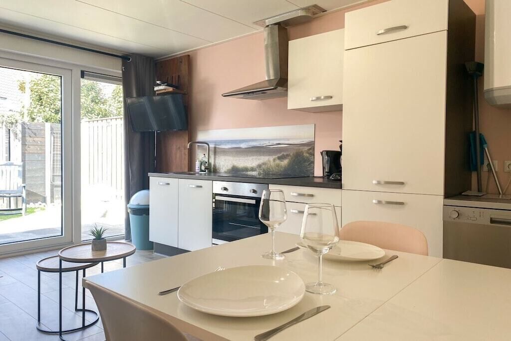 Une cuisine moderne avec une table à manger pour deux personnes, un four encastré et une grande fenêtre.