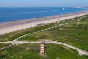 Eine Küstenlandschaft mit einem Leuchtturm, einem Strand und einer Straße, die zum Leuchtturm führt.