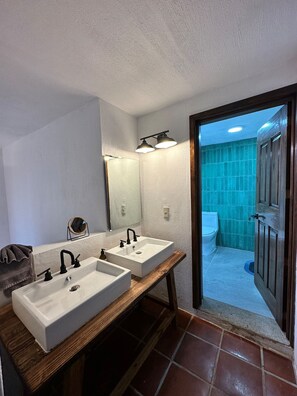 A bathroom with two sinks, a mirror, and a door leading to a shower area. - Mazamitla Villas Buenos Aires (Mazamitla)