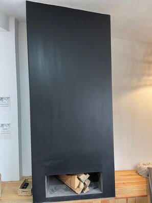 Una chimenea con panel frontal negro y un hogar visible en la parte inferior.