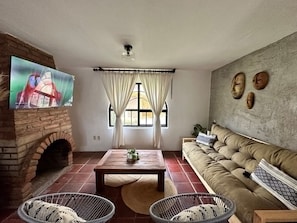 A living room with a brick fireplace, a television, a sofa, and a coffee table.