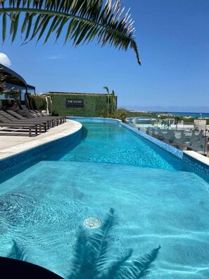 A swimming pool with lounge chairs and a view of the ocean. - The Shore PDC (Playa del Carmen)