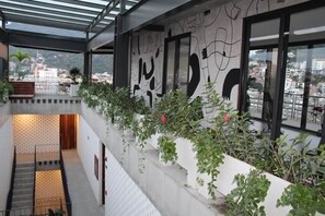 Ein mehrgeschossiges Interieur mit einer Treppe, einem mit Pflanzen bepflanzten Balkon und Blick auf die Stadtlandschaft.