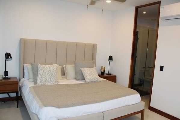 A modern bedroom with a large bed, two bedside tables, and a glass door leading to a bathroom. - Rincóndealmas Vta (Puerto Vallarta)