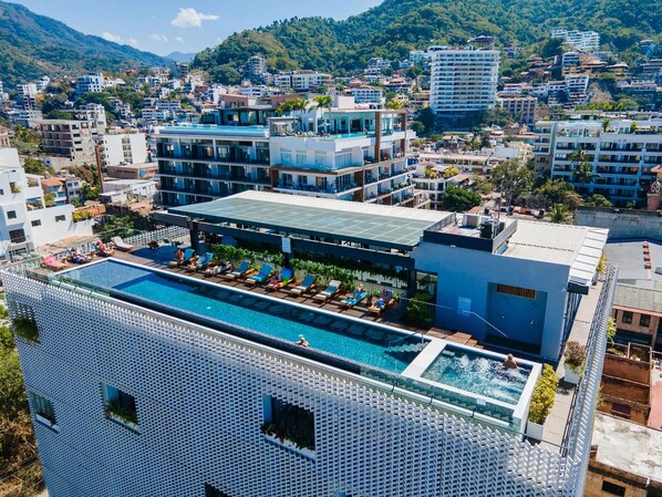 Ein Hotel mit Dachpool, mehreren Etagen und Blick auf die umliegende Stadtlandschaft.