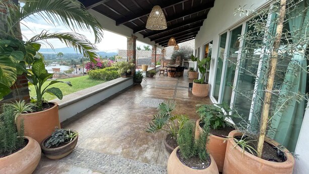 Un espace extérieur abrité, agrémenté de plantes en pot, d’une table de patio et de chaises.
