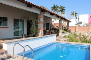 A pool area with a clear blue pool, a metal ladder, and a covered patio with potted plants. - Private Heated Pool - Lake View House - Golf Club (Chapala)